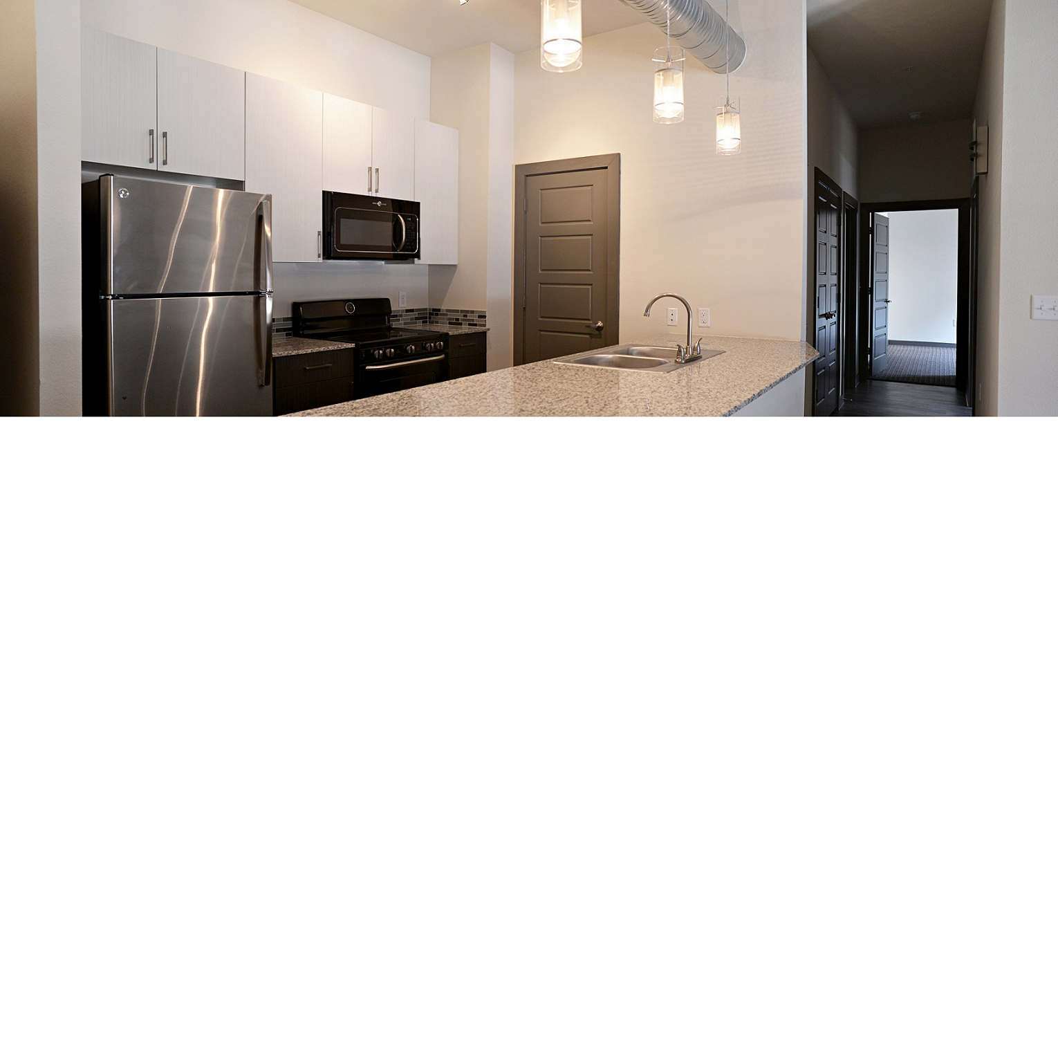 A kitchen with a stainless steel refrigerator and microwave. at East End Lofts at the Railyard Apartments, Denton, TX